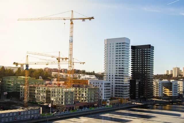 Modern buildings under construction with cranes.