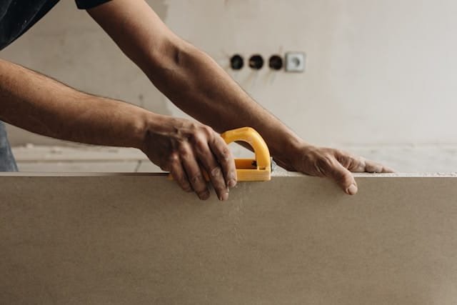 Person sawing drywall indoors