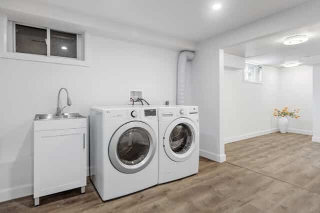 Modern laundry room with washer, dryer, and sink.